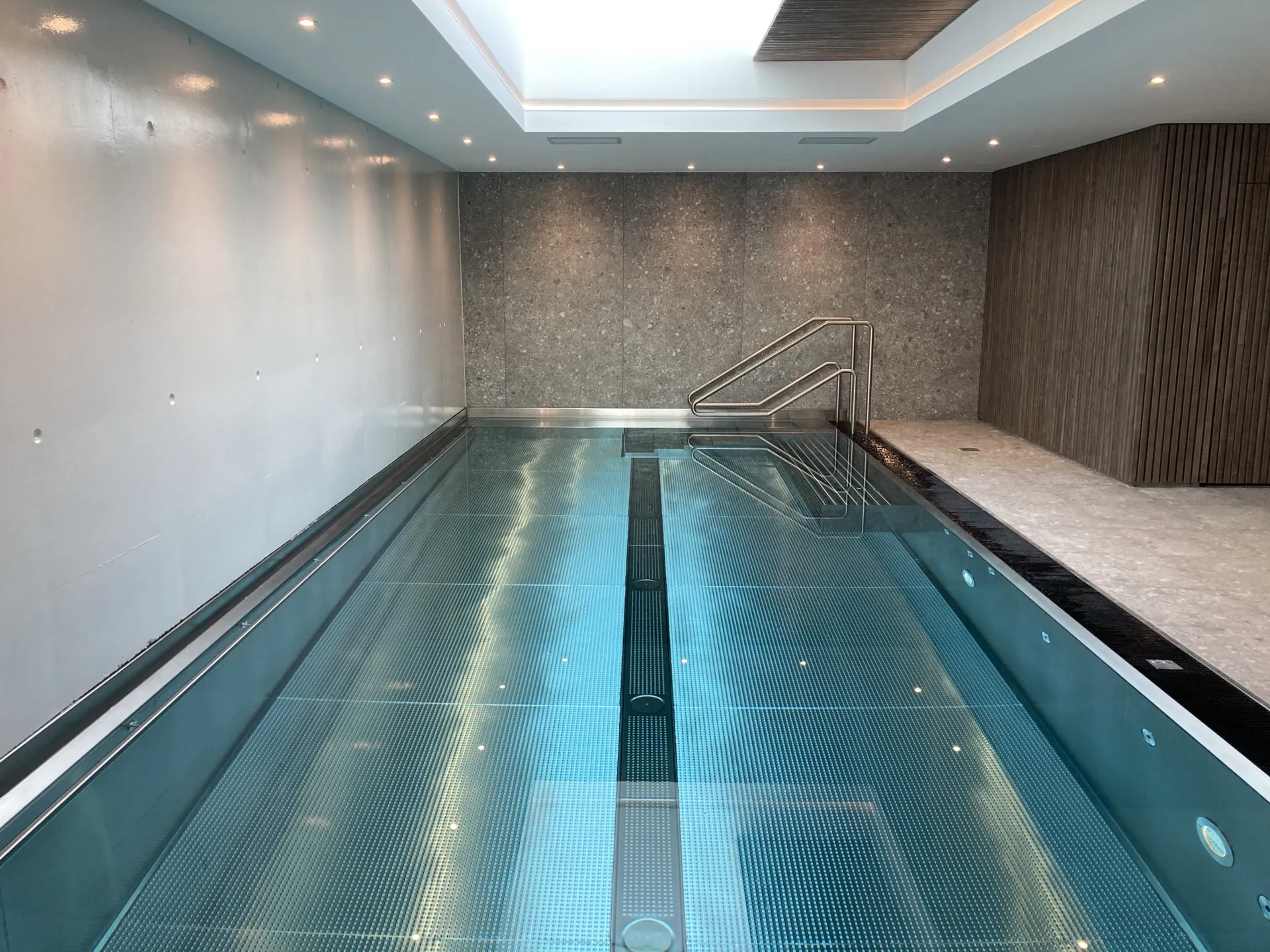 Bassin intérieur du Spa Le 34, bordé de murs minéraux et de lames de bois.