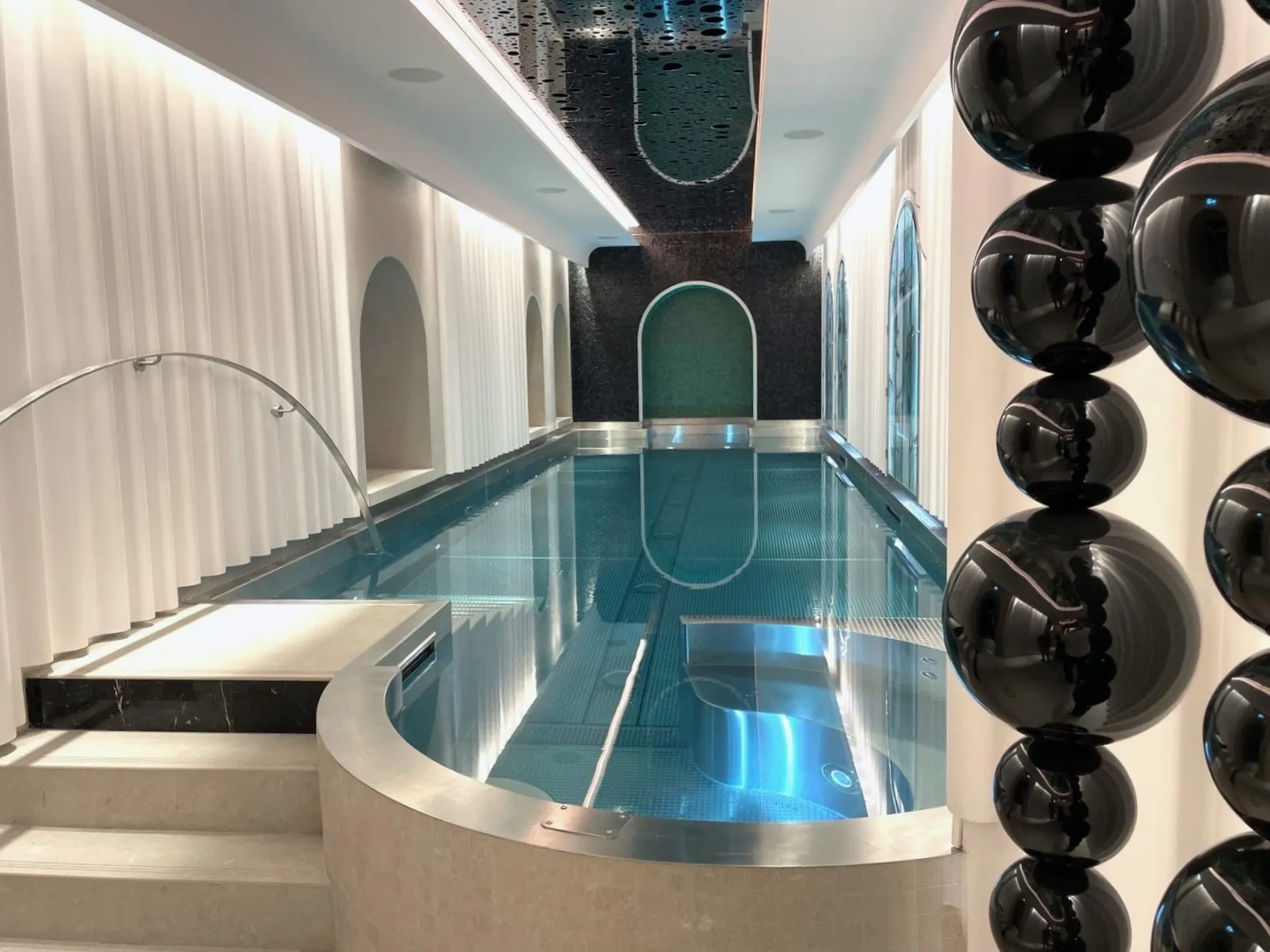 Bassin intérieur du Negresco avec spa arrondi, colonnes claires et sculptures noires.
